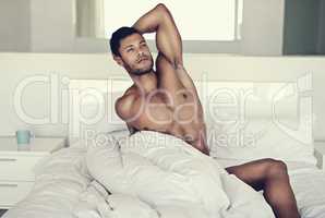 Homely hunkiness. Shot of a handsome naked man in bed in the morning.