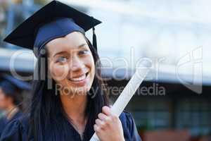 Upwards and onwards. A young college graduate smiling at the camera.