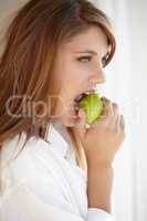 Biting into a juicy green apple. A beautiful young woman biting into a delicious apple.