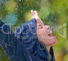 Feeling revived in the rain. Cropped shot of a young woman standing happily in the rain in her raincoat.