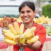 Fresh bananas. Portrait of a woman selling bananas at her market stall outside.