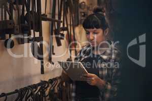 Old school trade meets new school technology. Shot of a young woman using a digital tablet while working at a foundry.