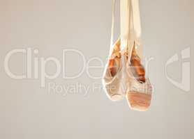 All ballet is dance, but not all dance is ballet. Shot of a pair on ballet shoes hanging in a dance studio.