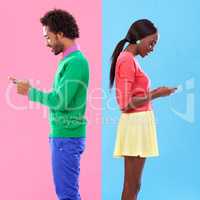 Opposites attract. Studio shot of a young couple using cellphoes standing against a colourful background.