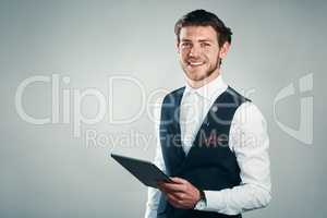 Technology is a big business asset. Studio shot of a handsome young businessman using a tablet against a grey background.