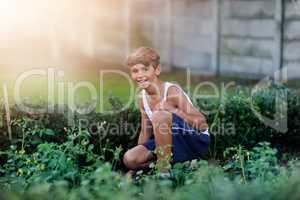 Hes quite resourceful in the garden. Portrait of a young boy gardening outside.