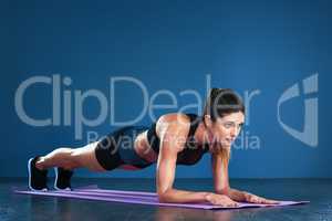 Planking is great for working out your whole body. Studio shot of a fit young woman posing against a blue background.