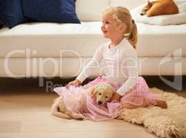 Doesnt she look pretty in her tutu. Shot of a little girl in a tutu playing with a puppy.