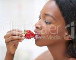 The forbidden fruit. Shot of a beautiful young woman eating strawberries.
