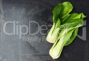 Leafy green goodness. Top view of leaves of chinese cabbage lying on a dark countertop.