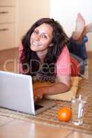 Instant access to information. A beautiful young woman lying on her floor at home and using a laptop.