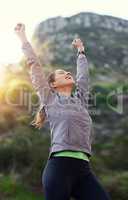 Theres nothing she cant achieve. Shot of a young woman with her arms raised in vicotry while out for a trail run.