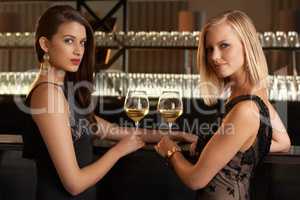 Evening style. Shot of two women standing at a bar in evening wear.