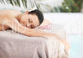 Tranquil treatments. A beautiful young woman lying on a massage table surrounded by rose petals.