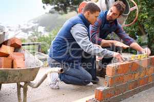 Making strong foundations - Teaching the basics. Shot of bricklayers at work.