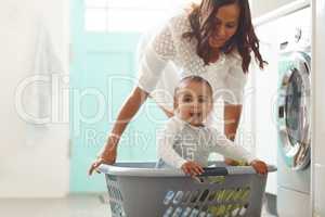 Im the pirate of this ship. Shot of a mother and her adorable baby boy doing the laundry at home.