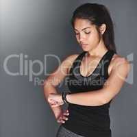 Getting more fit by the day. Shot of a fit young woman in sports clothing checking her watch.
