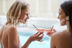 Poolside cocktails. Two friends tanning with cocktails in their hands.
