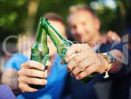 Beer is always the wise choice. Closeup image of two guys toasting their beer bottles at a music festival.