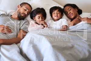 Our family is a dream come true. Shot of a beautiful young family of four fast asleep in bed together in their bedroom at home.