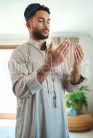 Prayer isnt asking. It is a longing of the soul. Shot of a young muslim man praying in the lounge at home.