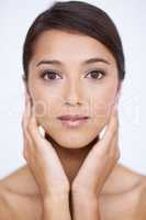 Her skin is both radiant and soft. A gorgeous young woman feeling her smooth, soft skin in a studio shoot.