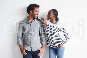 Absolutely smitten. A happy young couple standing together affectionately against a white wall.