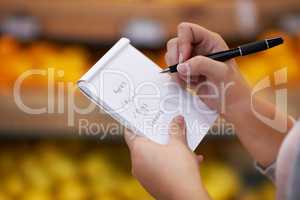 Ticking off her items as she goes along. Closeup shot of a woman checking her shopping list in a grocery store.