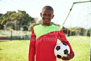 Wanna play some footy. Portrait of a young boy playing soccer on a sports field.