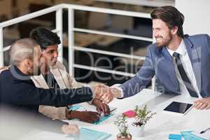 Creating business partnerships. Shot of businesspeople shaking hands in an office meeting.