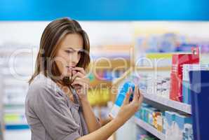 A young woman buying medicine in a pharmacy -The commercial designs displayed in this image represent a simulation of a real product and have been changed or altered enough by our team of retouching and design specialists so that they are free of any copy