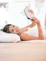 Bliss is having the time to read a good book. Portrait of a beautiful young woman lying in bed with her e-reader.