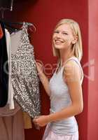 This dress will make her sparkle. Portrait of an attractive young woman picking out a dress from her wardrobe.