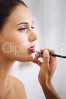 Beauty is a process. Cropped shot of a beautiful woman having lipstick applied with a makeup brush.