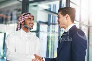 Business built on a mutual purpose. Shot of a young muslim businessman shaking hands with an associate in a modern office.