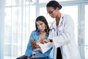 Ill send you some helpful health tips to you. Shot of a young doctor using a smartphone during a consultation with her patient.