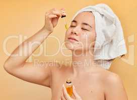 Make self care your number one priority. Shot of a young woman applying a serum to her face during her morning beauty routine against a yellow background.