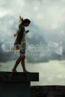 Living with abandon. Young woman walking on a rooftop with her arms outstretched.