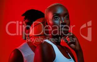 It takes two or more to play a game. Red filtered shot of a sporty young man and woman posing with a basketball in between them.