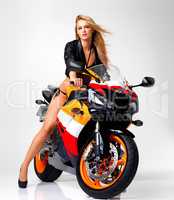 The hottest biker babe on two wheels. Studio portrait of a sexy young woman in a leather jacket and bikini riding a motorbike.