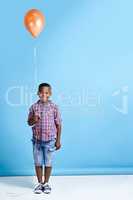 Look what Ive got. Shot of a young boy holding a balloon over a blue background.