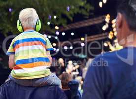 Best seat in the house. Rearview shot of a young boy sitting on his fathers shoulders at a music concert.