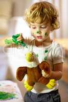Creativity doesnt play by the rules. Shot of an adorable little boy making a mess while painting.
