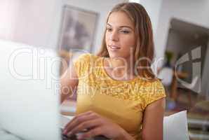 Unwinding with a bit of social media. Shot of a young woman using a laptop while sitting on a sofa at home.