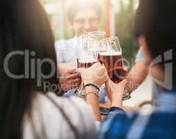 Whos buying the second round. Shot of a group of cheerful young business colleagues having a celebratory toast with beer around a table outside.