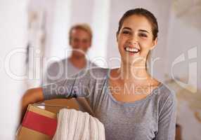 Moving onwards and upwards. Portrait of a young woman holding a box on moving day.