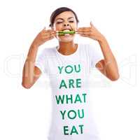 Om nom nom. Portrait of a young woman holding green beans while wearing a t-shirt saying you are what you eat.