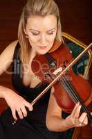 Soothed by the sound of her strings. A young woman sitting and playing a violin.