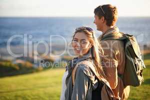 We go everywhere together. Portrait of a young couple standing on the edge of an embankment overlooking the ocean.