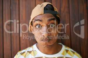 Never be too serious. Portrait of a teenage boy making a face while standing against a wooden wall.